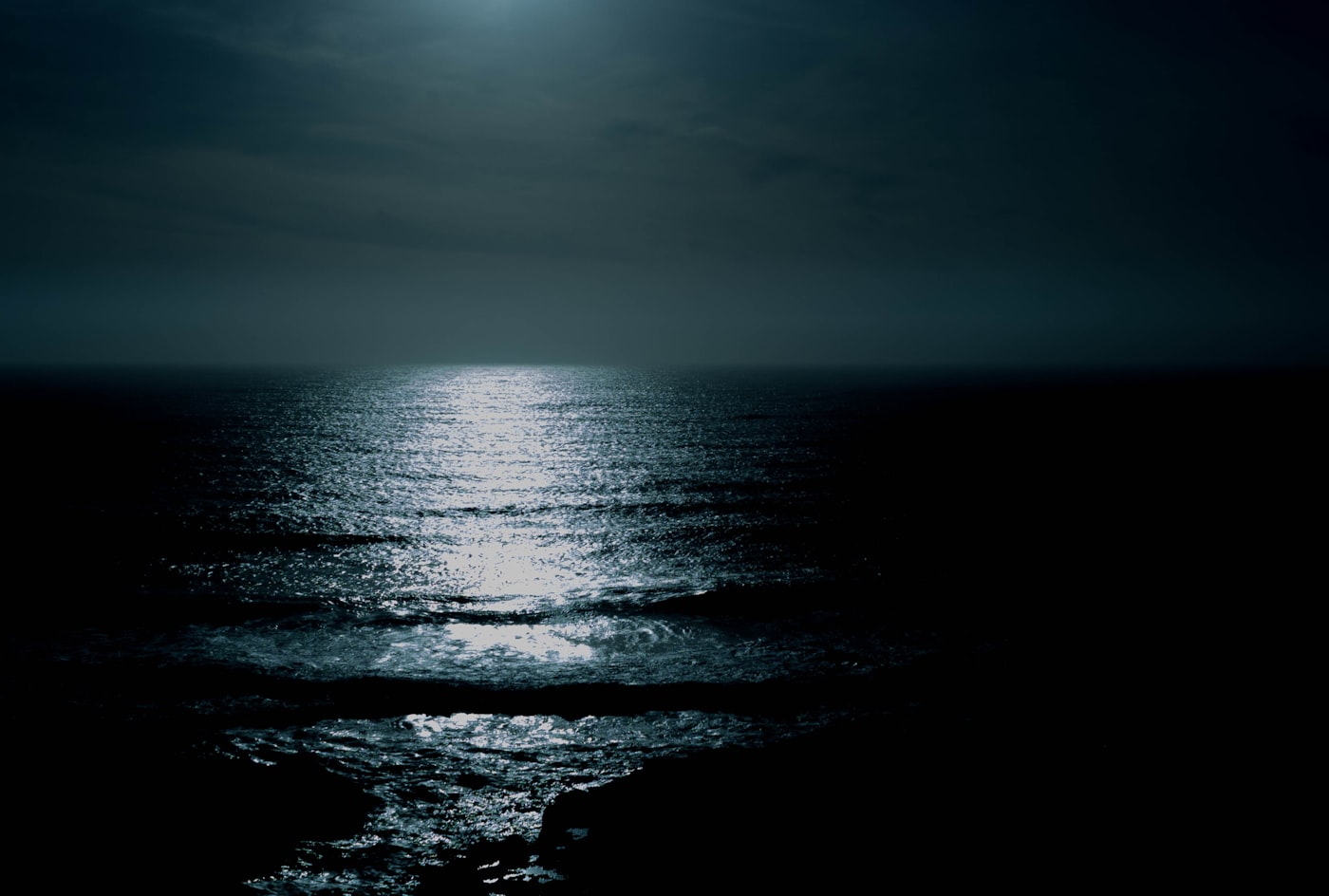 Full moon reflected on a dark, still body of water at night